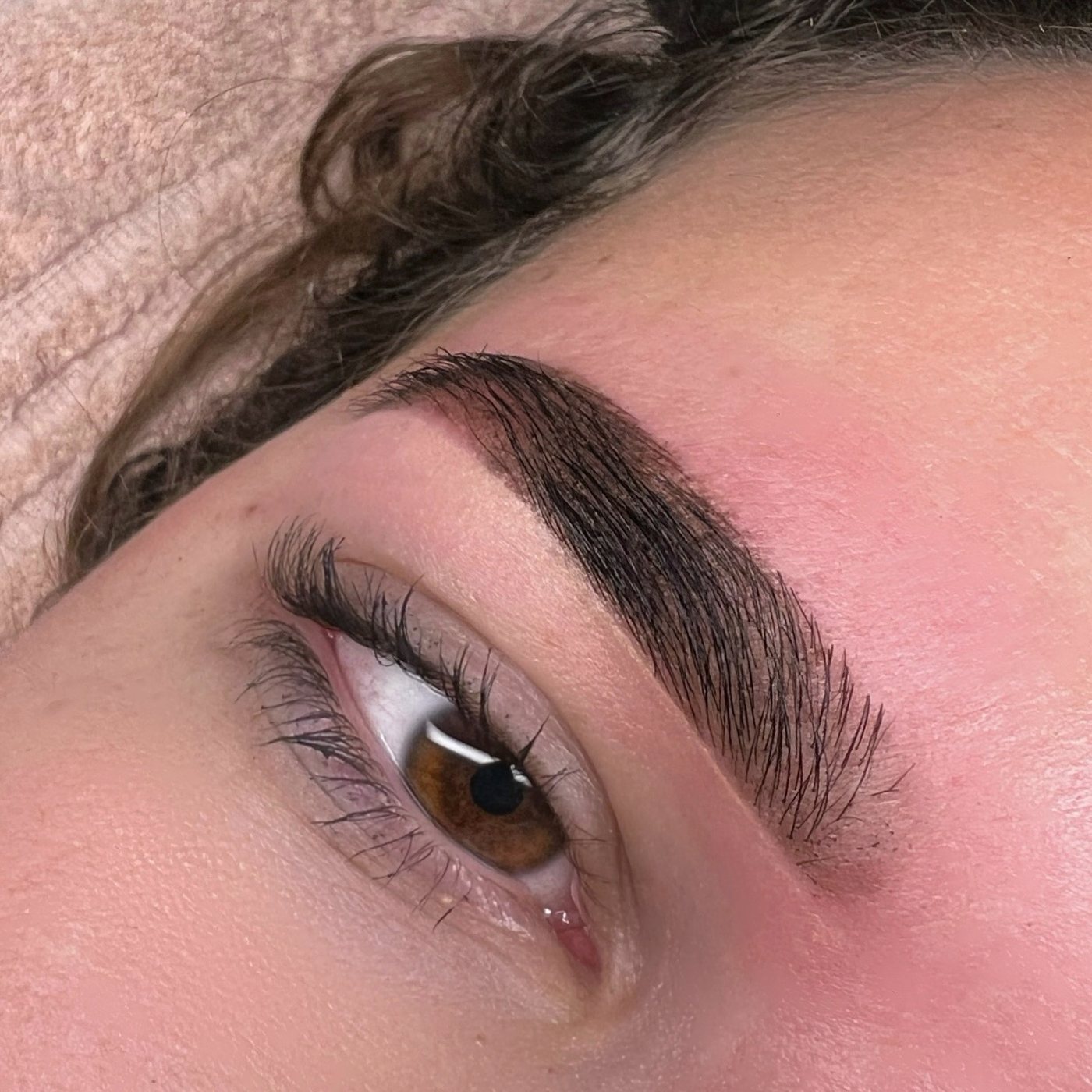 Volle, donkere wenkbrauw boven een bruin oog